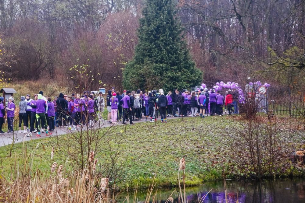 Tłum uczestników w fioletowych koszulkach na alejce przed startem